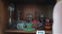 First photo showing an assortment of glass and colored acrylic candle holders on a wooden shelf.