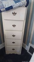 Front view of white painted chest with five drawers and brass handles.