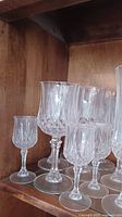Photo showing a group of crystal stemmed glasses with intricate cut patterns on shelves.