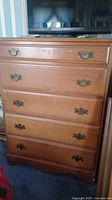 Front view showing all five drawers and metal handles on wooden dresser