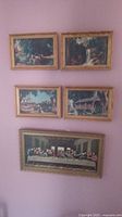 Five framed art pieces arranged on pink wall showing four vertically oriented smaller prints and one larger horizontal print of The Last Supper below.