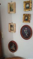 All six framed art pieces hanging on a corner wall, showing two rows with four rectangular pieces and two oval pieces below.