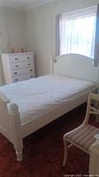 Diagonal front angle of white bed frame with headboard, footboard, and mattress visible