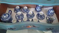Overview of entire tea set including teapot, cups, saucers, cream jug, and sugar bowl inside a wooden tray