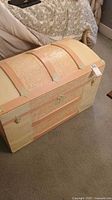 Front and top view of the pink and white painted steamer trunk showing textured decorative panels and metal locks.