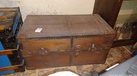 Full front view of vintage wooden steamer trunk showing metal hardware locks and worn wood surface.