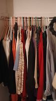 Photo showing multiple women's shirts hanging on hangers in various colors and styles.