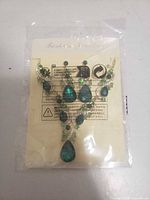 Front view of sealed necklace and earrings set showing design and stones