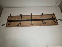 Front view of wood coat rack with five black metal double hooks