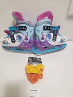 Side view of Disney Frozen kids ice skates and three scrunchies on card