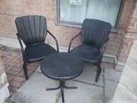 Two black metal patio chairs and round table