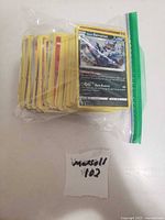 Stack of yellow-border Pokémon cards in zip bag, top card Hisuian Samurott 170 HP