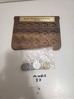 plaque empty with plastic bag of coins showing front view