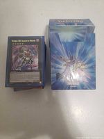Stack of Yu-Gi-Oh! cards next to Konami deck box, top card "Number C39: Utopia Ray Victory" visible