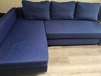 Front view of the navy blue L-shaped sectional sofa showing the seating area and back cushions on a wood floor.