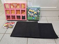 Group shot of both 1000-piece puzzles, CD game and black puzzle mat