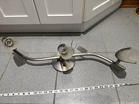 Overall top view of curved brushed steel track light with three frosted glass shades, tape measure showing length ~31 in