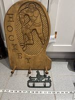 Wood hockey plaque with cast iron chicken hook rack displayed on floor