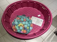 Overall view of pink hard plastic pool with mesh bag of balls and instruction sheet