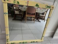 Full view of mirror reflecting dining area, shows yellow frame and motifs