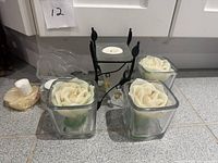 Entire lot showing three rose candles, metal stand with frosted cup, elephant holder, round tealight holder, wrapped candle