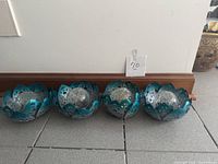 Four teal metal lotus solar lights lined together