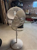 Full view of white pedestal fan showing blades, grille, stand and base