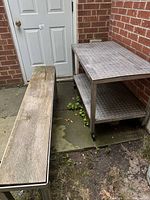 Work table and bench positioned outdoors against brick wall