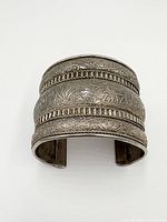 Front view showing detailed engraved floral patterns and braided silver bands on the wide cuff bracelet.