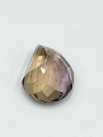 Close-up front angle of the faceted pear-shaped ametrine gemstone showing its bi-color purple and yellow hues.