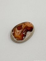 Close-up front view of the polished Boulder Opal showing detailed brown and orange color swirl patterns.