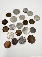 Multiple Canadian coins arranged on white background showing varying wear, colors, and one with a hole.