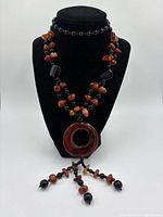 Front view of the necklace displayed on a black bust, showing the large circular carnelian pendant and bead arrangement.