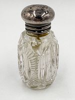 Front angled view of crystal bottle with sterling silver cap, showing intricate cut details and tarnished cap.