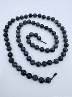 Full view of the longer 26-inch strand of lapis lazuli beads arranged in a loose circle on white background