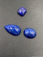 Top view of three lapis lazuli gemstones against black background showing color and shape detail.
