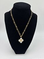 Full view of necklace on black display showing gold-tone double chain and pearl cluster pendant.