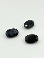 Three oval faceted sapphires shown on white background illustrating size, shape, and coloration.