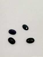 Four oval polished sapphire gemstones on a white background viewed from above.