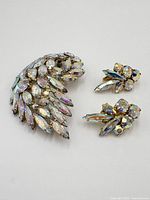 Full set of Sherman jewelry including the brooch and pair of earrings with aurora borealis rhinestones in gold tone setting, showing overall condition and sparkly stone details.
