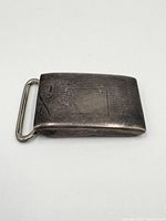 Close-up of the sterling silver belt buckle front side showing engraved decoration and slightly curved shape.