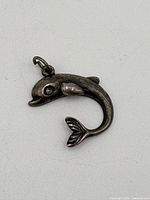 Front view of the sterling silver dolphin pendant showing the detailed head, eye, and curved body with tail and fins.