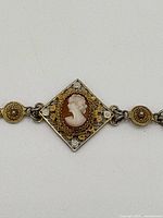 Close-up of diamond-shaped central cameo with gold vermeil filigree and decorative stones.