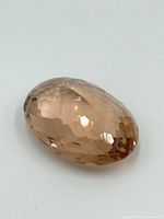Image showing the faceted oval topaz gemstone with a light brownish peach color from an angle.