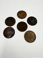 Top view of six various coins, including one 'ONE PENNY' coin and five others with visible wear and tarnish