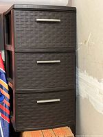 Photo of a black plastic storage drawer unit with three drawers, each drawer has a woven pattern front and a silver handle.