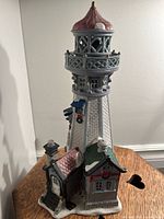 Full view of the ceramic lighthouse figurine on a wooden table against a white wall.