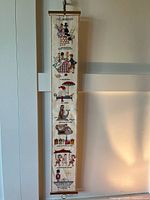Full view of the long, narrow embroidered tapestry hanging on the wall showing the entire length and scenes.