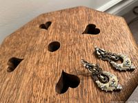 Photo of vintage enamel earrings on wooden surface, showing intricate design and condition.