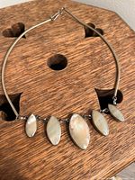 Necklace showing white marquise-shaped stones on pendants with a sleek metal collar